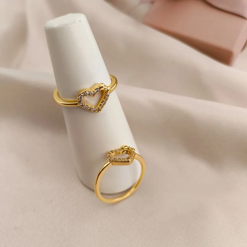 ANEL COM CORAÇÃO VAZADO CRAVEJADO EM MICRO ZIRCONIA COM LAÇO LISO NA PARTE DE CIMA