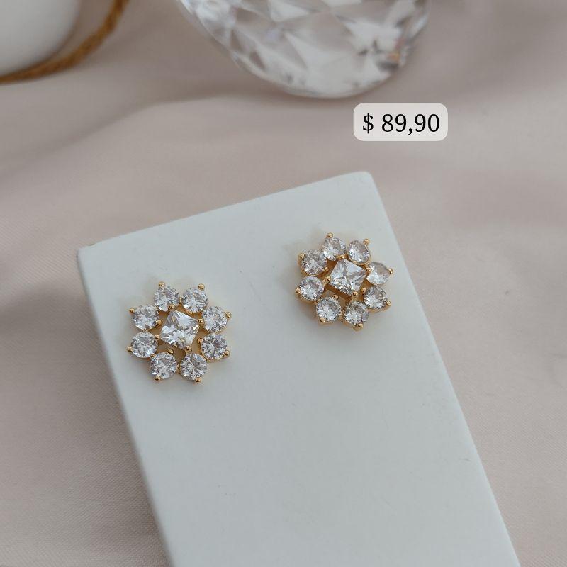 BRINCO EM FORMA DE FLOR COM PEDRA QUADRADA NO MEIO E PEDRAS REDONDAS AO REDOR